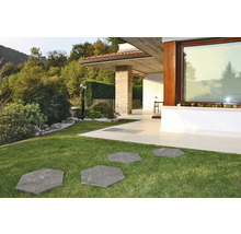 Záhradný chodník zo šesťhranných kamenných dosiek v trávniku pred moderným domom.