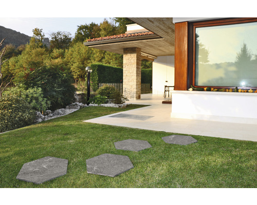 Záhradný chodník zo šesťhranných kamenných dosiek v trávniku pred moderným domom.