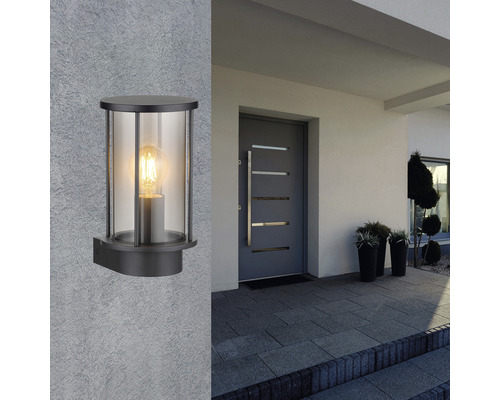 Čierne nástenné svietidlo s čírym sklom na stene domu vedľa vchodových dverí.