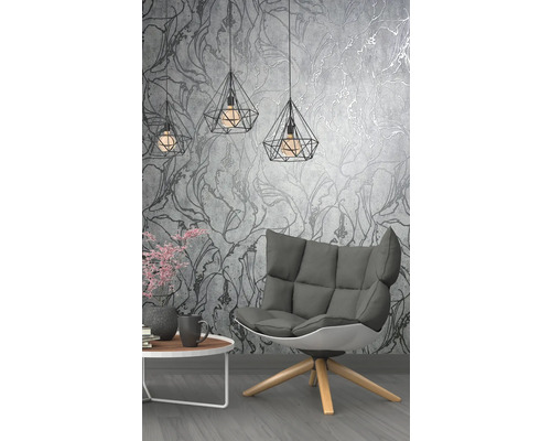 Obývacia izba s kreslom, stolom a geometrickými závesnými lampami pred kvetinovou tapetou