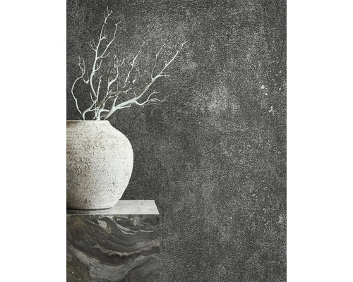 Detail vázy s konármi pred tmavou, štruktúrovanou stenou