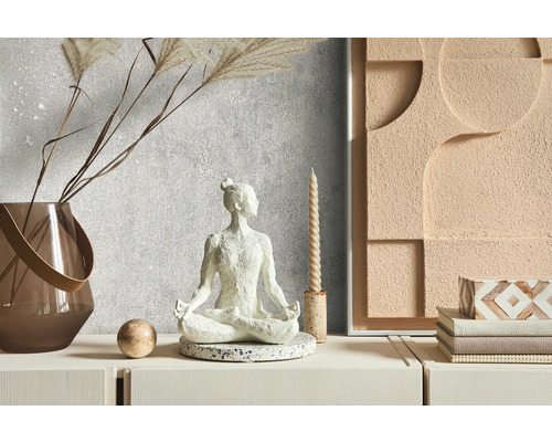 Dekoratívna scéna s meditačnou figúrkou, vázou, sviečkou a nástennou dekoráciou na komode.