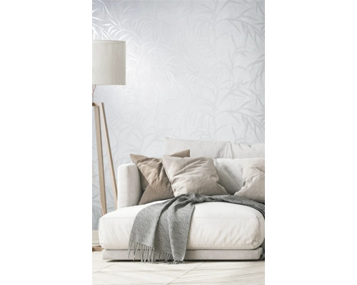 Obývacia izba s pohovkou, vankúšmi, dekou, stojacou lampou a tapetou s rastlinným vzorom