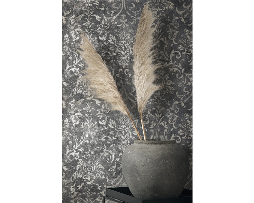 Dekoratívne perie v kameninovej váze pred vzorovanou tapetou