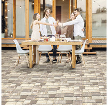 Scéna s ľuďmi sediacimi vonku pri stole s dlažobnými kockami v popredí.