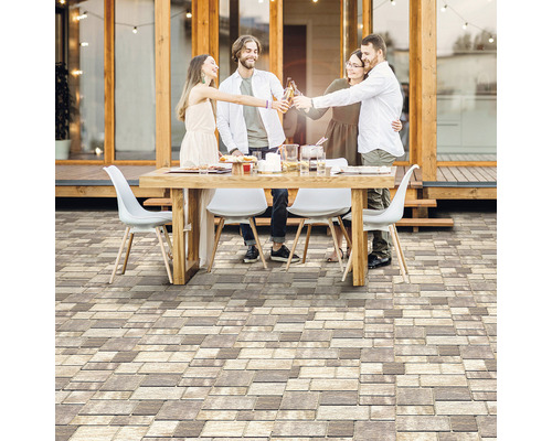 Scéna s ľuďmi sediacimi vonku pri stole s dlažobnými kockami v popredí.