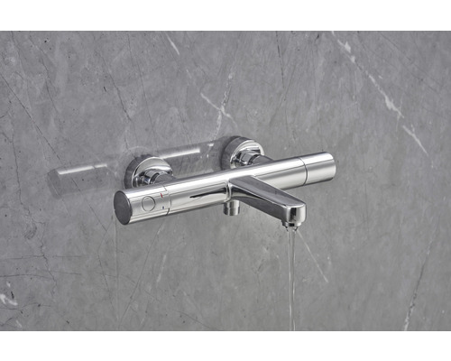 Nástenná sprchová batéria pred sivou stenou s prietokom vody