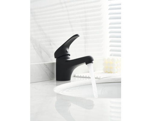 Čierna vodovodná batéria s tečúcou vodou na umývadle