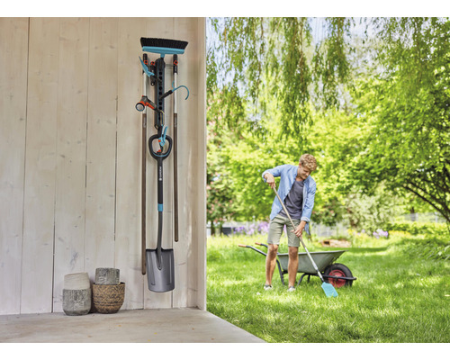 Záhradná scéna s držiakom na náradie, záhradným náradím a osobou pracujúcou v záhrade