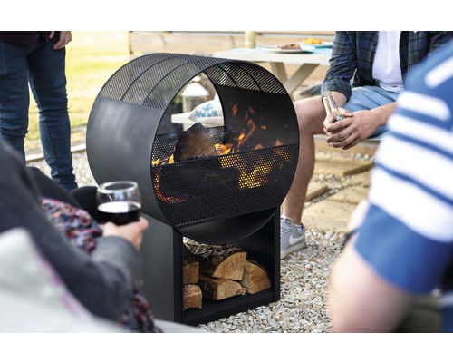 Kruhové kovové ohnisko so skladom dreva na záhrade s ľuďmi