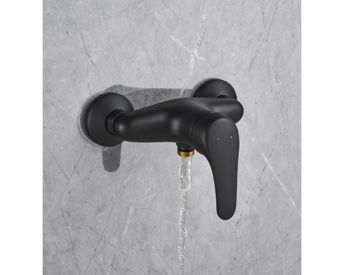 Čierna sprchová batéria s tečúcou vodou na stene