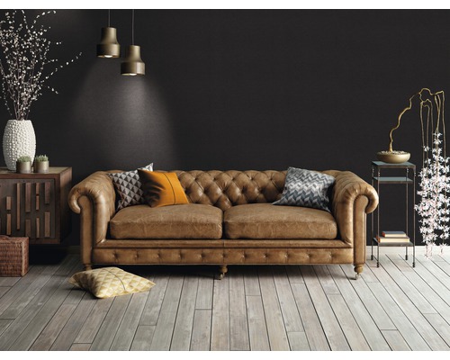 Obývacia izba s hnedou koženou sedačkou v štýle Chesterfield, drevenou podlahou a dekoratívnymi prvkami