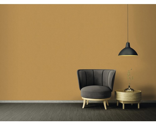 Obývacia izba s kreslom, príručným stolíkom a závesnou lampou pred jednofarebnou stenou