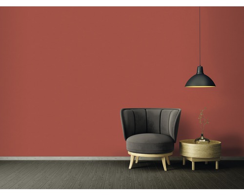 Obývacia izba s kreslom, príručným stolíkom a závesnou lampou pred farebnou stenou