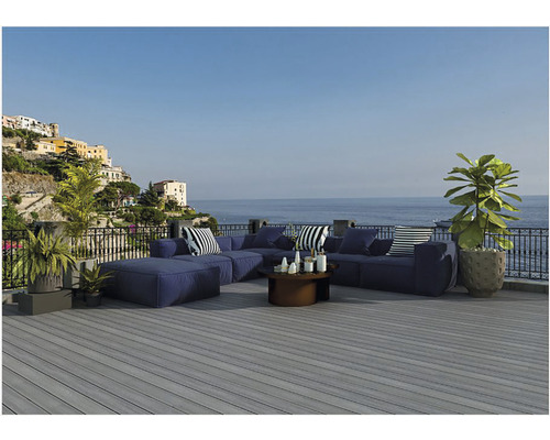 Pohľad zhora na sivú drevenú terasu s modrým záhradným nábytkom a výhľadom na more