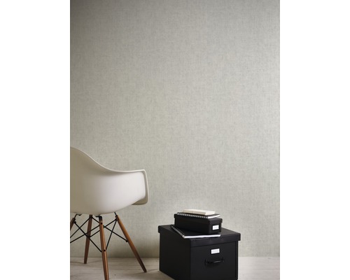 Interiérová scéna so svetlou tapetou, bielou stoličkou a čiernymi úložnými boxmi