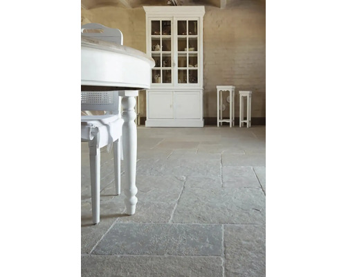 Interiér s kamennou dlažbou, bielym stolom a vitrínou