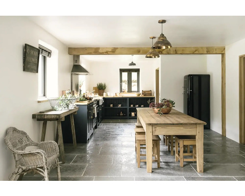 Svetlá vidiecka kuchyňa s drevenými trámami, jedálenským stolom, stoličkami a kuchynskou linkou