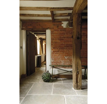 Interiér s tehlovou stenou, drevenými trámami a kamennou podlahou