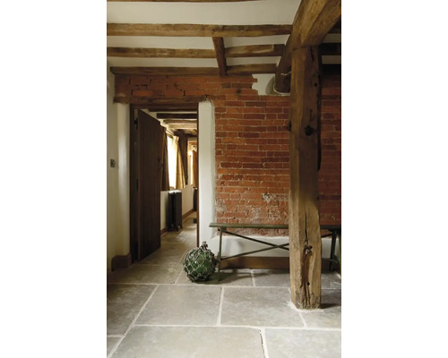 Interiér s tehlovou stenou, drevenými trámami a kamennou podlahou