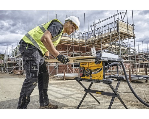 Stavebný robotník obsluhuje stolovú pílu na stavenisku.