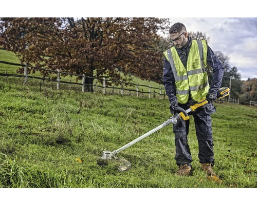 Osoba vonku zastrihuje trávu akumulátorovým vyžínačom.