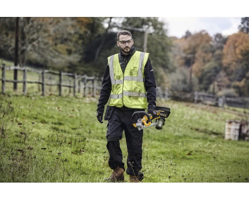 Muž s bezpečnostnou vestou a akumulátorovou pílou vonku