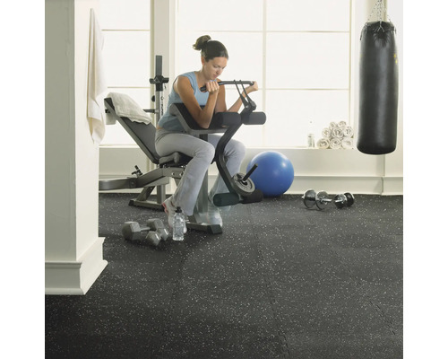 Posilňovňa so ženou cvičiacou na lavici s činkami na gumenej podlahe