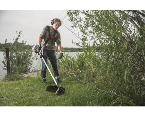 Muž obsluhuje vyžínač na brehu jazera s ochrannými okuliarmi a slúchadlami