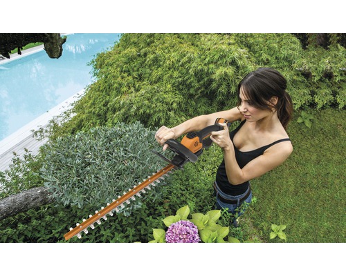 Žena strihá živý plot nožnicami na živý plot v záhrade.