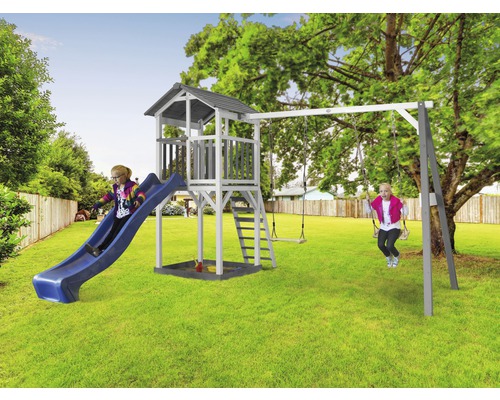 Dieťa na šmýkačke a dieťa na hojdačke pri hracej veži s pieskoviskom v záhrade.