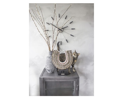 Dekoratívne zátišie s hodinami, vázou s vetvami, sochou a mačkou na skrini