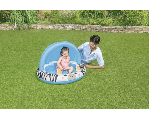 Nafukovací detský bazén so vzorom zebry a slnečnou strieškou v záhrade s hrajúcim sa dieťaťom a dospelým
