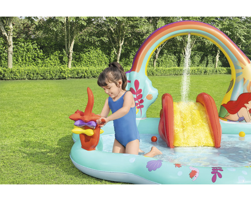 Dieťa sa hrá v nafukovacom bazéniku so šmýkačkou a vodnými hrami v záhrade
