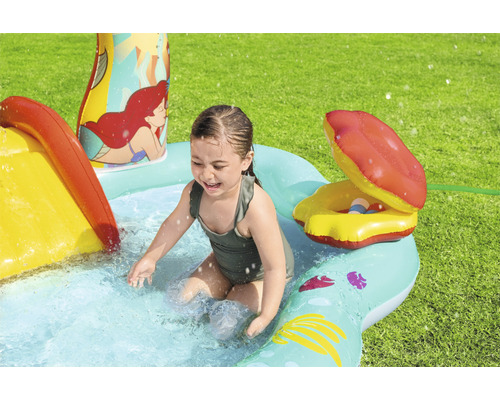 Dievča sa hrá v nafukovacom bazéniku so šmýkačkou a vodným postrekovačom