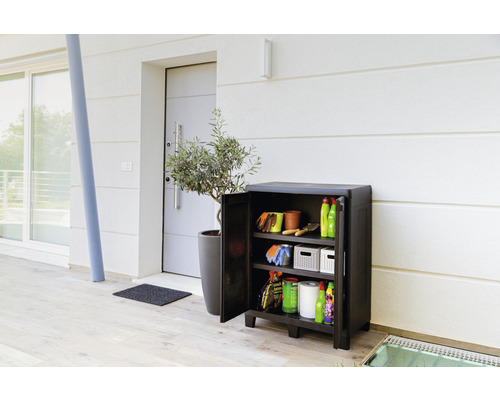 Záhradná skrinka s otvorenými dverami, plná záhradného náradia pred domom