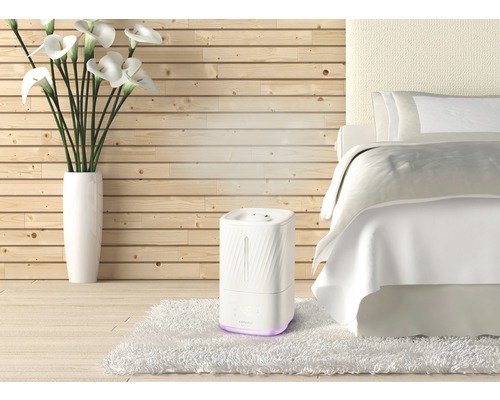 Zvlhčovač vzduchu v spálni s posteľou a drevenou stenou