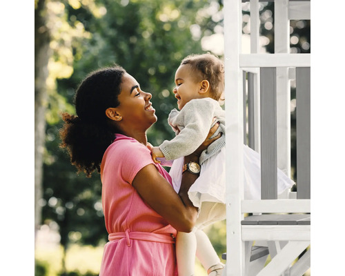 Matka drží smejúce sa dieťa na hracej konštrukcii v záhrade