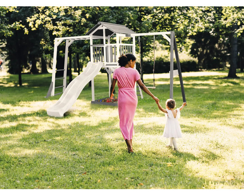Detské ihrisko so šmýkačkou, hojdačkou a herným domom v záhrade so ženou a dieťaťom
