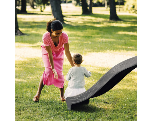 Matka a dieťa s detskou šmýkačkou v záhrade