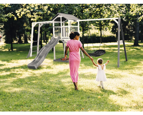 Detské ihrisko s vežou, šmýkačkou a hojdačkou v záhrade, žena drží dieťa za ruku