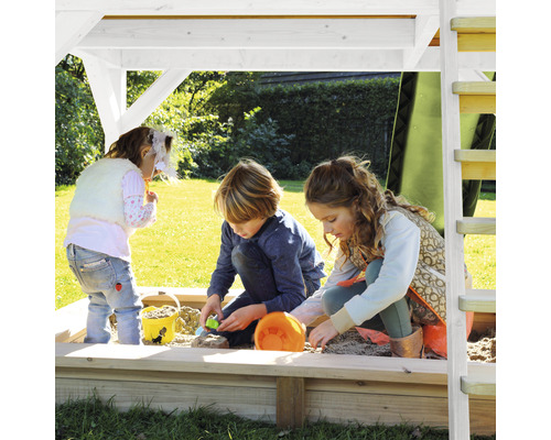 Deti sa hrajú na trávniku v pieskovisku pod hracou vežou