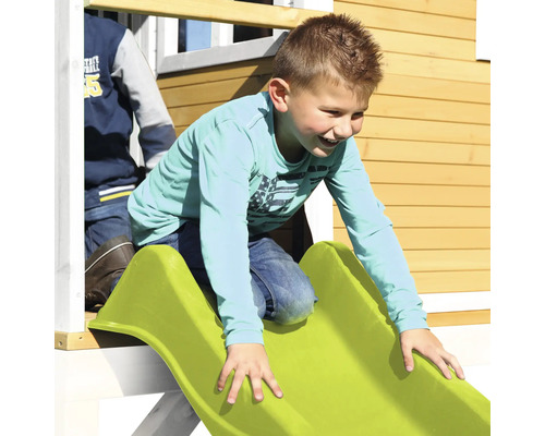 Chlapec sa šmýka na zelenej šmýkačke z hracieho domčeka