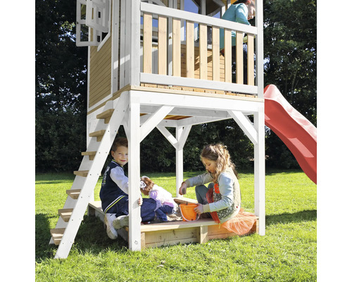 Detský domček so šmýkačkou a pieskoviskom s hrajúcimi sa deťmi v záhrade