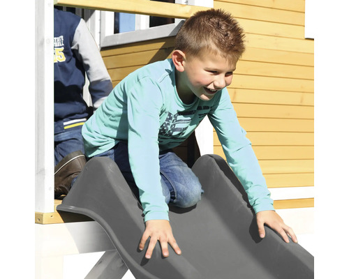 Chlapec sa šmýka na šmýkačke pri hernom domčeku