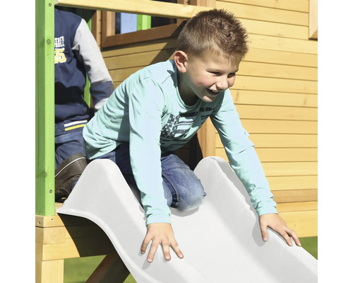 Chlapec sa šmýka na bielej šmýkačke detskej veže.