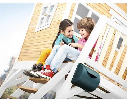 Dve deti sedia na schodoch dreveného domčeka na hranie s poštovou schránkou.