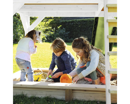 Tri deti sa hrajú v pieskovisku so strechou na zelenej ploche.