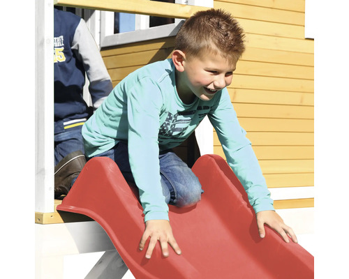 Chlapec sa šmýka na červenej detskej šmýkačke na detskom ihrisku.