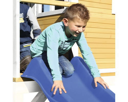 Chlapec sa šmýka po modrej šmýkačke v hracom domčeku.